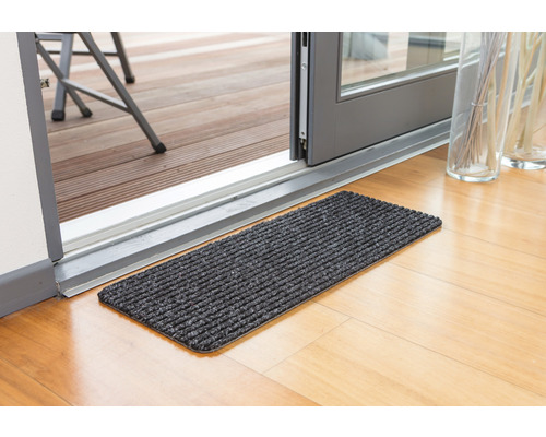 Tapis de sol devant une porte de terrasse sur un plancher en bois