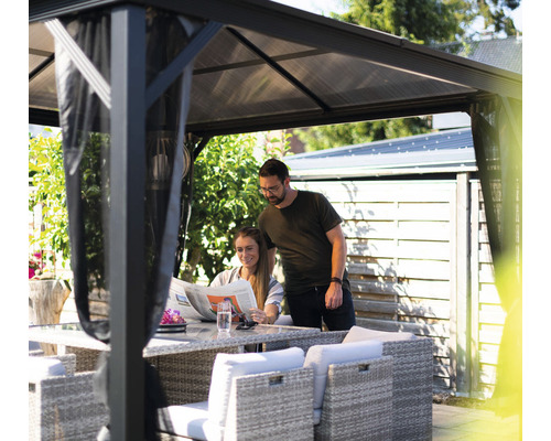 Un couple se détend sous un pavillon de jardin avec table et chaises dans le jardin.