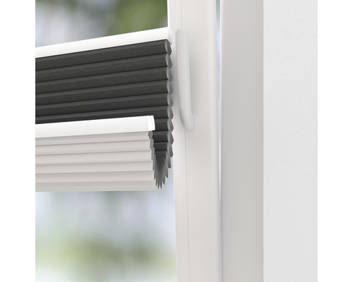 Nahaufnahme einer grauen und weißen Faltjalousie am Fenster