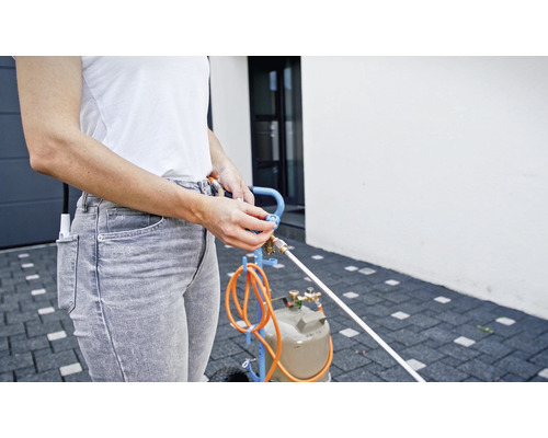 Une femme utilise un désherbeur thermique avec cartouche de gaz à l''extérieur.