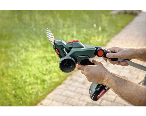 Person hält Metabo Akku-Rasenkantenschere im Garten