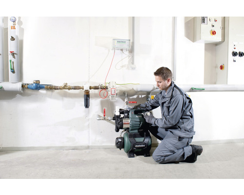 Ein Mann installiert eine Metabo Hauswasseranlage in einem Installationsraum.