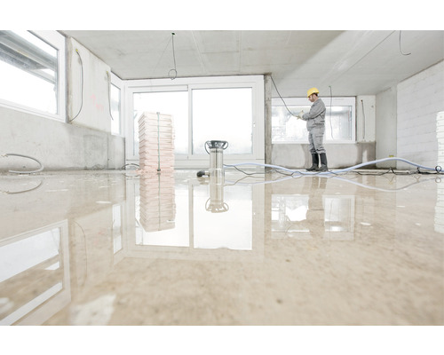 Chantier avec travailleur, aspirateur à eau et sol inondé