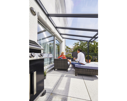 Terrasse couverte avec barbecue et sièges dans le jardin