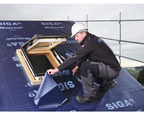 Un couvreur installe un écran de sous-toiture autour d''une fenêtre de toit.