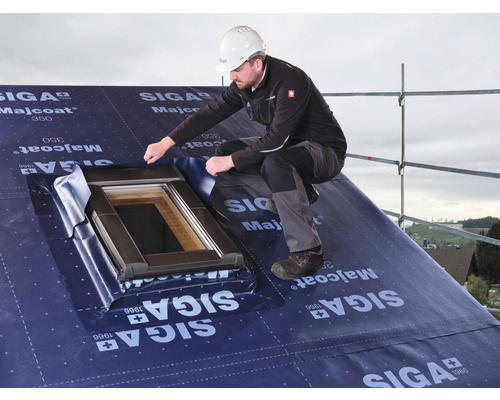 Un artisan pose une sous-toiture SIGA Majcoat 350 autour d''une fenêtre de toit sur un toit.
