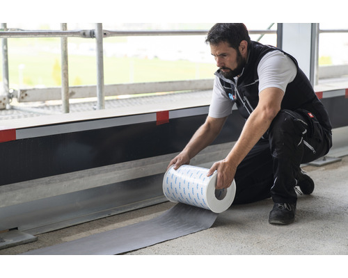 Un homme pose une bande d''étanchéité sur un chantier