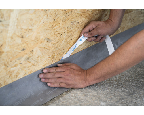 Application de ruban d''étanchéité de fenêtre avec du ruban adhésif d''étanchéité sur une plaque de bois