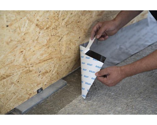 Une personne fixe une bande d''étanchéité sur une plaque de bois.