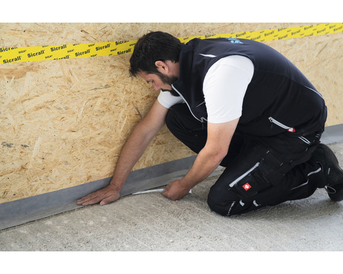 Handwerker befestigt Dichtungsband an einer Wand aus Holzwerkstoffplatten