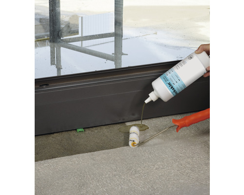 Person trägt Dichtstoff mit einer Rolle auf eine Türschwelle auf.