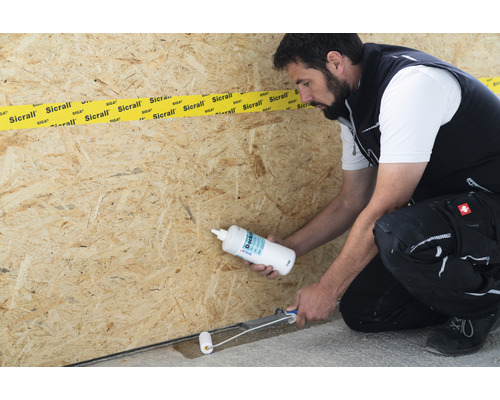 Mann trägt Dichtstoff mit einer Rolle auf Holz auf