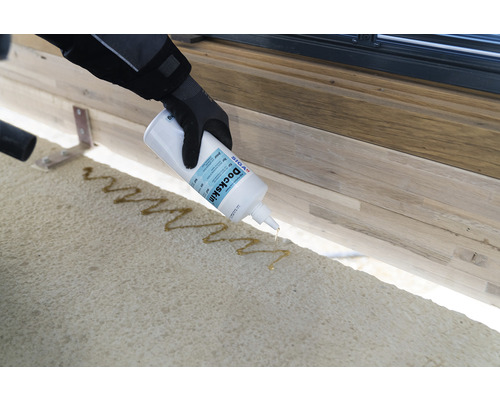 Person trägt Klebstoff mit einer Flasche auf