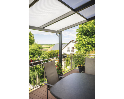 Terrasse avec toit, table et chaises devant un paysage verdoyant