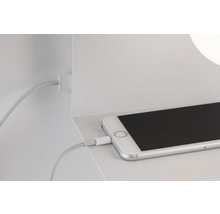 Smartphone avec câble de chargement sur étagère blanche
