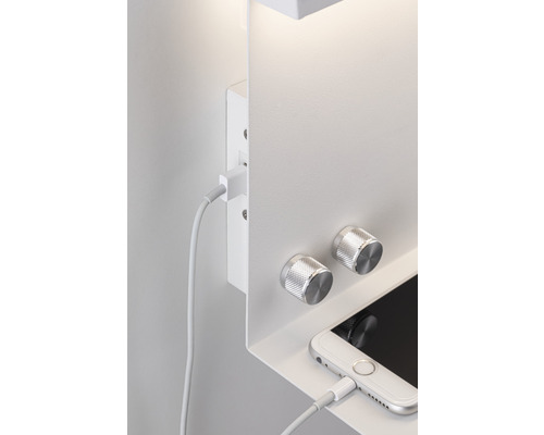 Weisse Wandleuchte mit Reglern und einem Mobiltelefon, das an ein Ladekabel angeschlossen ist