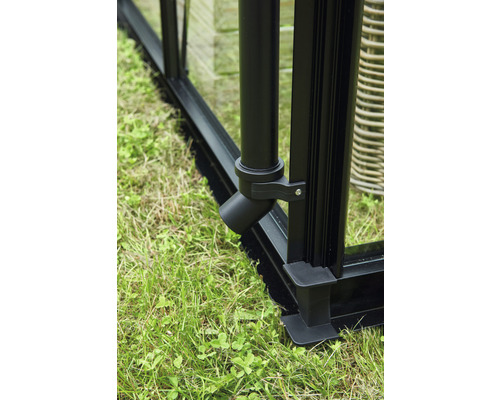 Detailaufnahme eines schwarzen Gewächshaus-Ablaufsystems am Fundament auf Gras