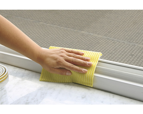 Person reinigt Fensterrahmen mit einem Tuch