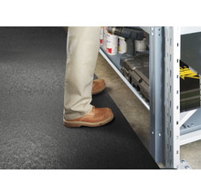 Szene mit einer Person, die vor einem Regal auf einer Bodenmatte steht