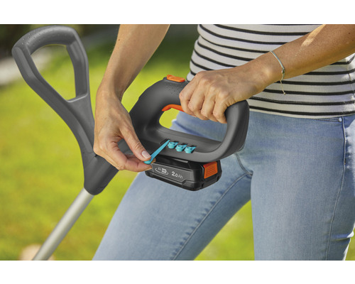 Eine Frau bedient einen Rasentrimmer mit Akku