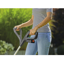Frau bedient einen Akku-Rasentrimmer im Garten.