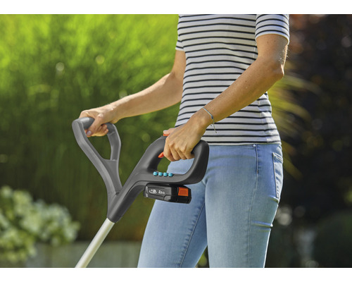 Frau bedient einen Akku-Rasentrimmer im Garten.