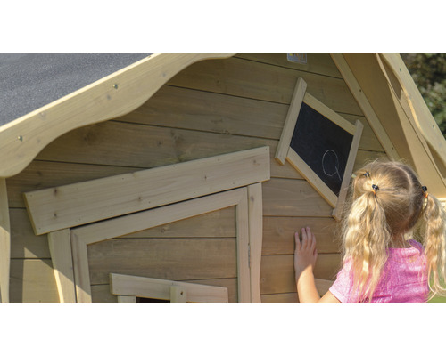 Detailansicht eines Kinderspielhauses aus Holz mit Kreidetafel, an der ein Mädchen malt.