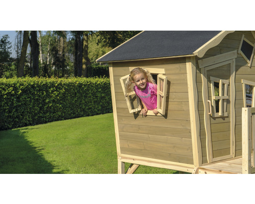 Kind spielt in einem Holzspielhaus mit Fenster im Garten.