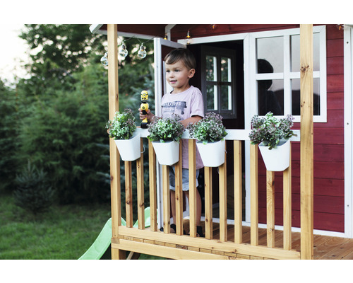 Maisonnette avec garçon, jardinières et jouets sur la véranda dans le jardin