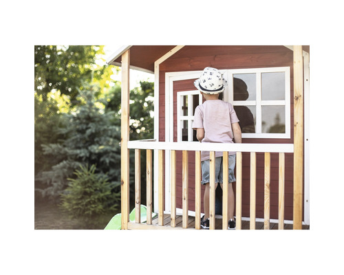 Un enfant se tient sur la véranda d''une cabane en bois