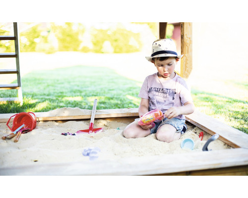 Garçon jouant avec des jouets dans un bac à sable