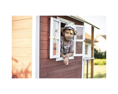 Un enfant regarde par la fenêtre d''une cabane de jeu