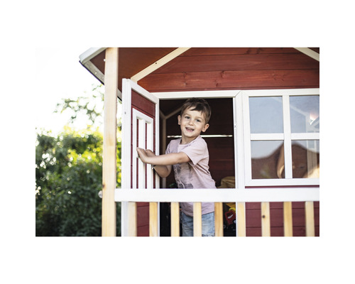 Garçon jouant dans une cabane en bois avec fenêtre et porte