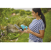 Frau hält eine Gardena Akku Grasschere mit wechselbaren Messern in der Hand.