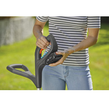 Eine Person befestigt einen Akku an einem Rasentrimmer.