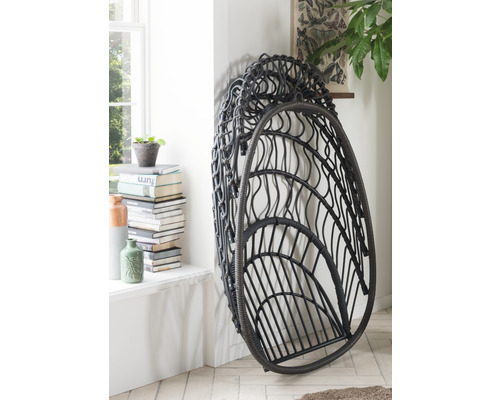 Hängesessel aus Rattan im Innenraum, an einer Wand stehend.