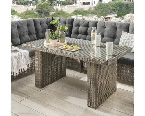 Table de jardin avec plateau en verre et surface en rotin sur une terrasse