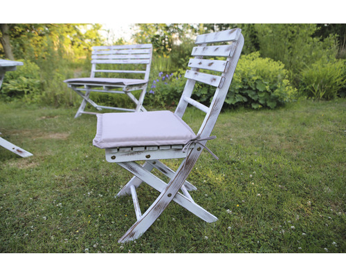 Scène de jardin avec chaises pliantes en bois blanc et coussins d''assise