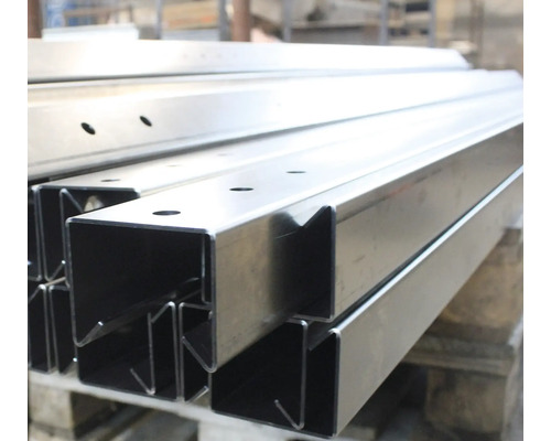 Profilés en acier avec trous empilés sur une palette.