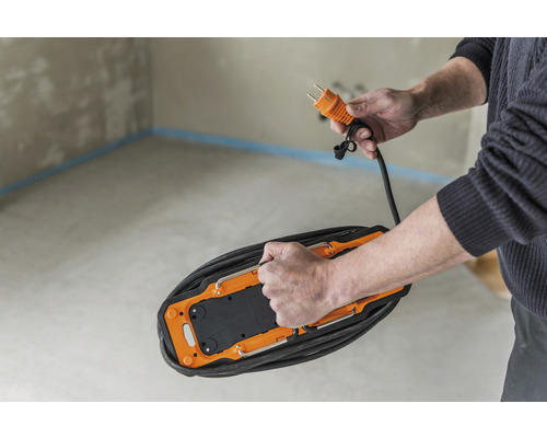 Person hält eine Kabeltrommel mit Stecker in der Hand.