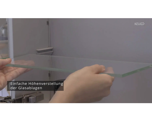 Person setzt ein Glasregal in einen Badspiegel Schrank von Keuco ein.