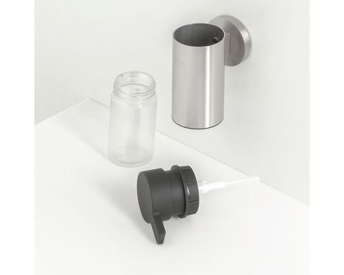 Wandseifenspender aus Edelstahl mit leerem Glasbehälter und schwarzem Spenderkopf