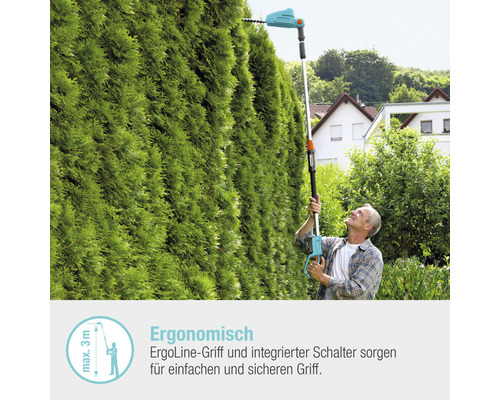 Mann schneidet Hecke mit einer elektrischen Heckenschere mit Teleskopstiel