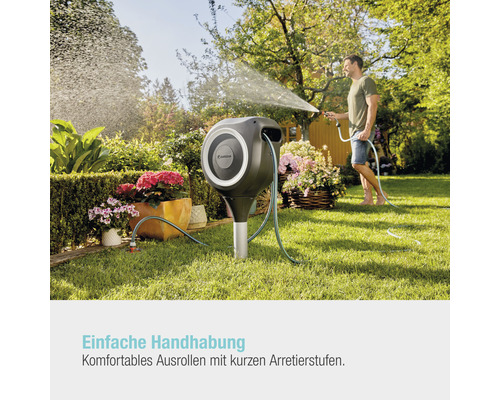 Gartenszene mit Schlauchbox und einem Mann, der mit einem Gartenschlauch gießt