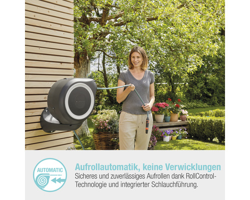 Frau mit einer an der Wand montierten Schlauchtrommel im Garten
