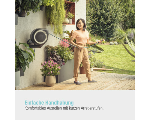 Frau benutzt eine Schlauchtrommel im Garten.
