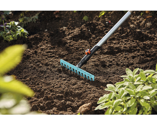 Râteau de jardin avec manche en métal utilisé sur un parterre de fleurs