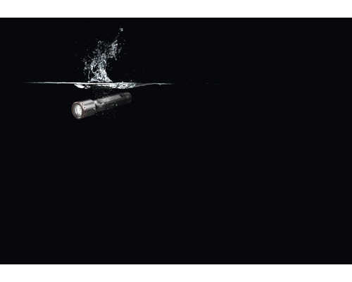 Une lampe de poche étanche tombant dans l''eau et éclaboussant.