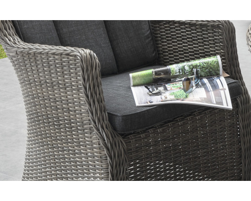 Detailansicht eines Rattansessels mit Sitzkissen und Zeitschrift