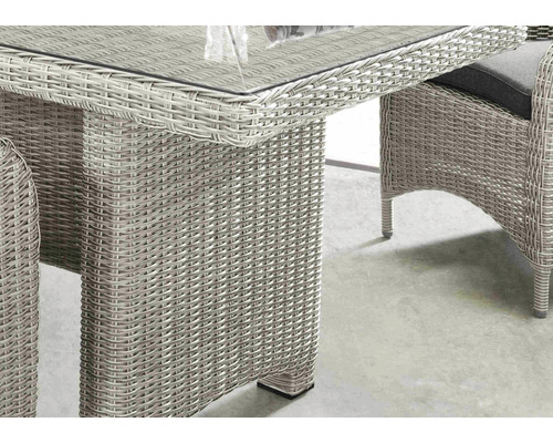 Vue détaillée d''une table de jardin avec surface tressée et plateau en verre.